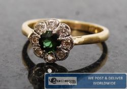 A ladies 18ct gold diamond and emerald claw set daisy / solitaire ring. The central set emerald