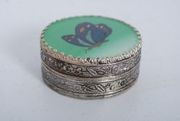 A Chinese white metal ladies pill box having embossed decoration, inset butterfly acryllic top with
