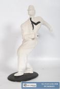 A plaster figure of a jazz style dancing man, with black tie, dancing the twist. On a black rounded