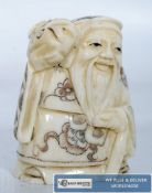 A bone carving of an oriental figure with Chinese decoration to surface.