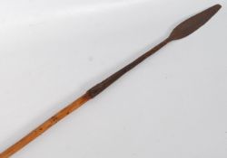 An African tribal spear. The carved and polished shaft having a short arrow head on long cylindrical