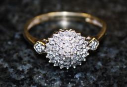 A 9ct gold pave set diamond cluster solitaire ring. The raised pave set diamond head set on plain