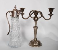 A silver plate candlestick, along with a silver plate glass claret jug with ornate Baccus figural