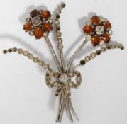 Silver metal ladies flower brooch with diamond chip stems and amber stone head, tied with ribbon.