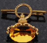 A yellow gold pin brooch having revolving amber stone.