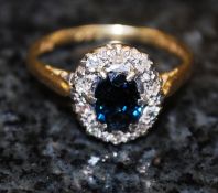 An 18ct gold diamond and sapphire solitaire ring. The central set emerald with diamond surround