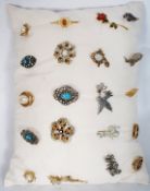 20 costume brooches on a display cusion to include glass, stone and enamel examples in various