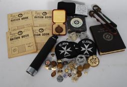 A collection of military related badges, WWII ration books, St Johns Ambulance etc.