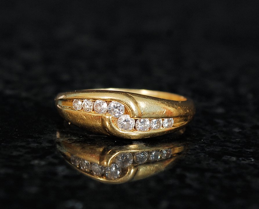 A ladies 18ct gold channel set diamond ring. The diamonds approx 25pts set within a crossover