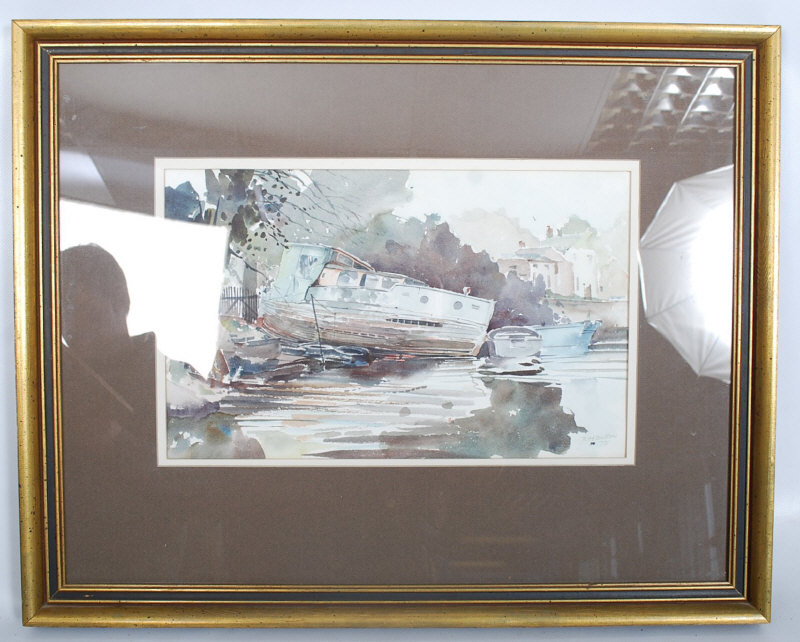 RM Bolton. Framed and glazed watercolour of beached river boat. Signed to lower corner. 40cm x 25cm