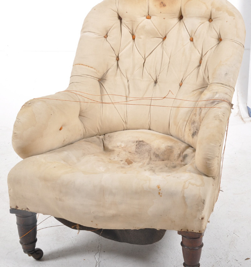 A Victorian button back armchair raised on mahogany turned legs ready to be re-upholstered