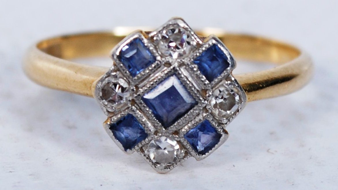 An 18ct gold ladies solitaire ring with cornflower sapphire stone surrounded by diamonds to the
