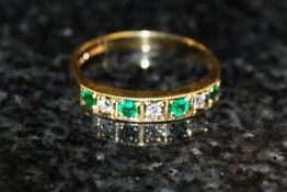 An 18ct gold emerald and diamond half eternity ring. The 4 emeralds flanked by diamonds.