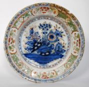 An 18th century delft bowl / charger with floral blue pattern. 34cm diameter. AF.