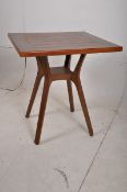 A contemporary hardwood bistro table stood on angular supports, sourced from local Hotel, 25
