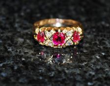 An 18ct gold ruby and diamond half eternity ring. The central set ruby stones (3) having diamond