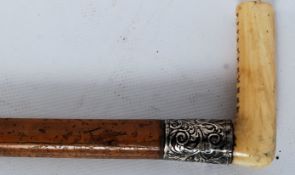 A 19th century walking cane having ivory handle and bearing a silver metal collar, and brass end.