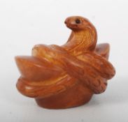 A Chinese boxwood carving of a snake wrapped around a coin, with inset black eyes. 5cm