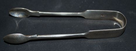 A pair of silver sugar tongs being hallmarked for London 1910 by Josiah Williams & Co - George