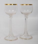 A pair of Victorian cut glass fluted wine goblets with gilt decoration having hollow stems. 19cm