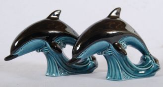 A Poole Pottery pair of studio dolphins with a mottled blue base. 17cm x 24cm.
