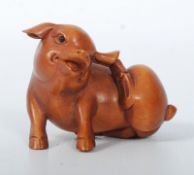 A carved boxwood miniature pig with inset black eyes. 4cm wide.