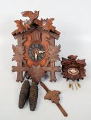 A black forest clock havgin decorative face with weights and chain together with a smaller black