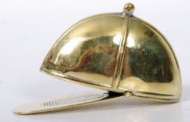 A brass vesta in the form of a horse riding Jockey`s cap, the cap`s peak acting as a hinged lid.