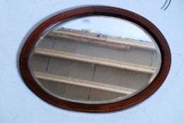 An antique oval mirror with inlaid edging. 60cm wide.
