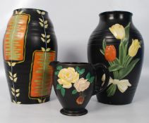 Two Brentleigh ware vases in black with foliate design along with a pouring jug. 28cm.
