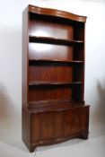 A Regency style mahogany inlaid library bookcase cabinet. The shaped serpentine base cabinet having