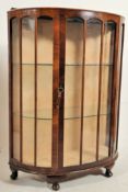 A 1930's walnut demi lune display cabinet. The cabriole legs with pad feet having a half moon shaped