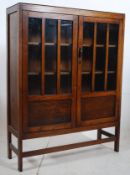 A 1930's Art Deco oak bookcase display cabinet. Squared legs supporting a twin door cabinet having