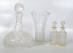 A cut glass ships decanter with stopper along with 2 cut glass scent bottles and a vase decanter.