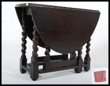 A Jacobean revival oak drop leaf dwarf occasional table. The barley twist legs united by