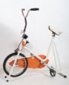 A 1970's retro Kettle exercise bike with original spring saddle in white and orange (working