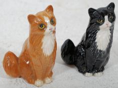 2 Royal Doulton cat figurines, one ginger, the other black and white. Both having Royal Doulton back