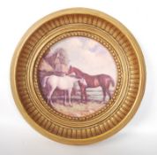 A porcelian painted picture of two horses in a decorative ornate gilt frame.