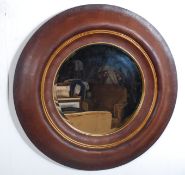 A large circular wall mirror having a leather frame and decorative gilt border