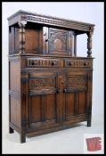 A carved oak jacobean revival court cupboard. Panelled doors with carved drawers finished with a
