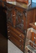 A 1930's Jacobean Revival oak tallboy / chest cabinet having carved pictorial and linen fold panel