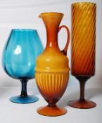 Three large coloured glass vases including one in the form of a jug.