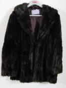 A faux mink fur ladies coat in a size 12 being short to the hip.