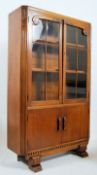 1930's Art Deco solid oak bookcase display cabinet. The shaped feet supporting a twin door cabinet