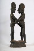 An african trival art hardwood carved figure of 2 embracing warriors. 58cms High