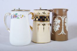 Three decorative jugs, 2 having silverplate hinged lids, the other being brown with jasperware