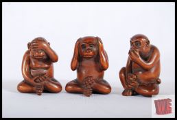 Three carved wooden netsukes in monkey form representing 'Hear No Evil, See No Evil, Speak No Evil.'