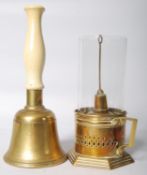 A brass hand bell and brass and glass chamber stick