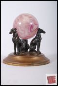 A desk paperweight with three bronze dogs supporting a blue/purple ball. Signed to base '