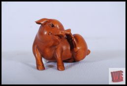 A carved wood netsuke of a pig with inset black eyes and Chinese marks to base. 3cm tall.